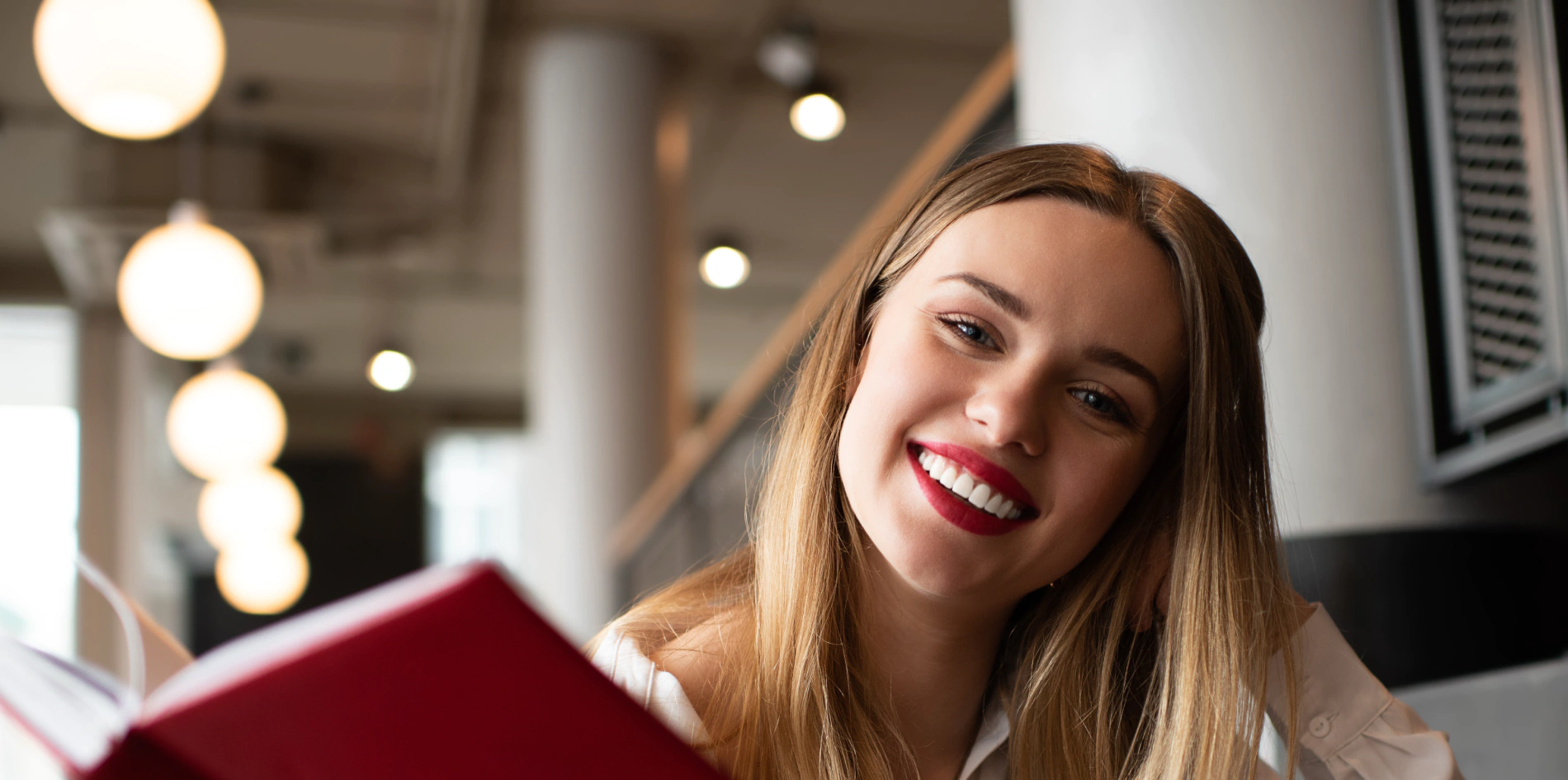 zdjęcie przedstawia młodą kobietę czytającą w restauracji