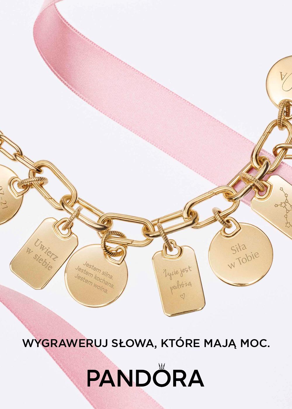 Otwarcie salonu Pandora w Galerii Solnej – złota bransoletka z grawerowanymi zawieszkami z inspirującymi hasłami na różowym tle, promująca personalizowaną biżuterię.