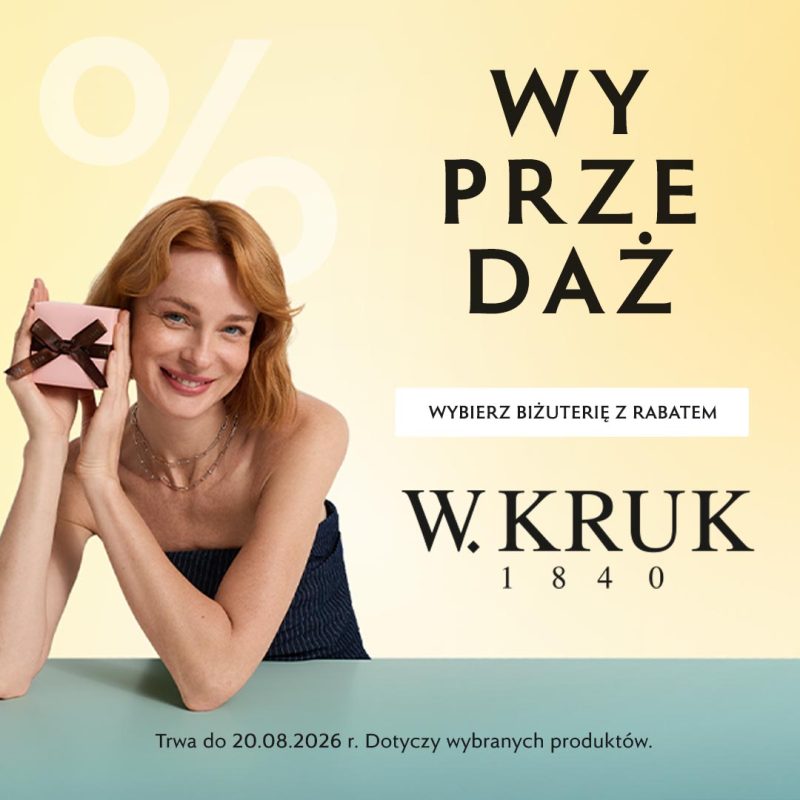 Baner reklamowy marki W.KRUK ogłaszający wyprzedaż na jasnym, pastelowym tle z dużym, półprzezroczystym znakiem procentu. W prawym górnym rogu znajduje się czarny, podzielony na sylaby napis „WY PRZE DAŻ”, a pod nim biały przycisk z hasłem „WYBIERZ BIŻUTERIĘ Z RABATEM”. Po lewej stronie uśmiechnięta, rudowłosa modelka trzyma przy twarzy małe, różowe pudełeczko przewiązane brązową wstążką. Pod napisem wyprzedażowym widnieje duże, czarne logo „W.KRUK 1840”. Na samym dole, na jasnoniebieskim pasku, umieszczono informację: „Trwa do 20.08.2026 r. Dotyczy wybranych produktów.”.