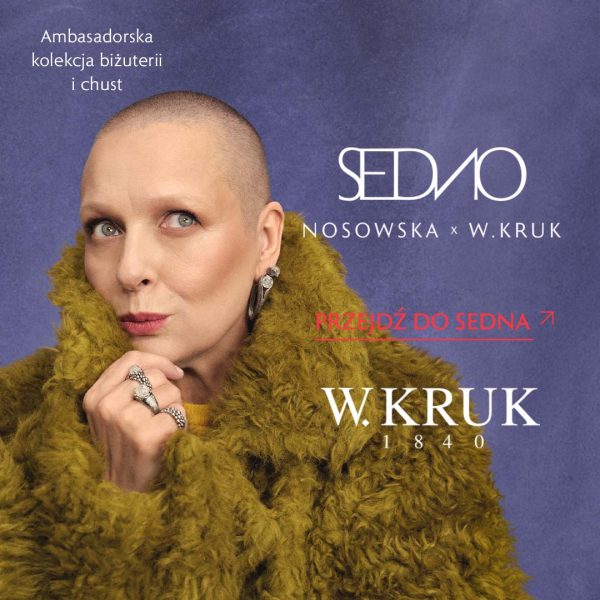Baner wizerunkowy marki W.KRUK przedstawiający wokalistkę Kasię Nosowską w oliwkowym, puszystym płaszczu na fioletowym tle, prezentującą biżuterię z autorskiej kolekcji. Na jej palcach widoczne są ozdobne pierścionki, a w uchu wiszący kolczyk. W lewym górnym rogu znajduje się napis „Ambasadorska kolekcja biżuterii i chust”, po prawej stronie stylizowane białe logo kolekcji „SEDNO NOSOWSKA x W.KRUK”, czerwony napis z wezwaniem do działania „PRZEJDŹ DO SEDNA” oraz klasyczne logo „W.KRUK 1840”.