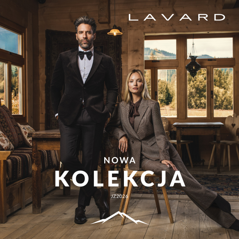 Baner promocyjny marki LAVARD w eleganckim, drewnianym wnętrzu, przedstawiający stojącego mężczyznę w ciemnym garniturze z muszką oraz siedzącą na krześle kobietę w brązowym garniturze w kratę. W lewym górnym rogu za oknami widać górski krajobraz. W prawym górnym rogu umieszczono białe logo „LAVARD”, a na środku w dolnej części widnieje duży biały napis „NOWA KOLEKCJA JZ2026” wraz ze stylizowaną grafiką przedstawiającą zarys górskich szczytów.